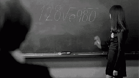 a black and white photo of a girl writing on a blackboard