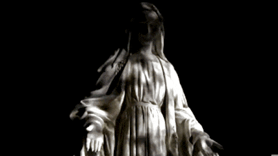 a statue of a woman with her arms outstretched in front of a black background
