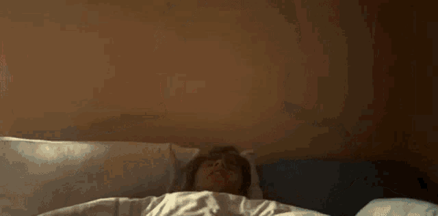 a young man is laying on a bed with a pillow .