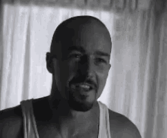 a bald man with a beard wearing a white tank top
