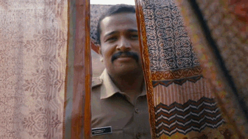 a man in a uniform is peeking out of a doorway .