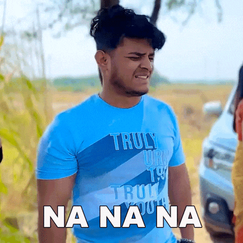 a young man wearing a blue truly youth t-shirt is making a funny face