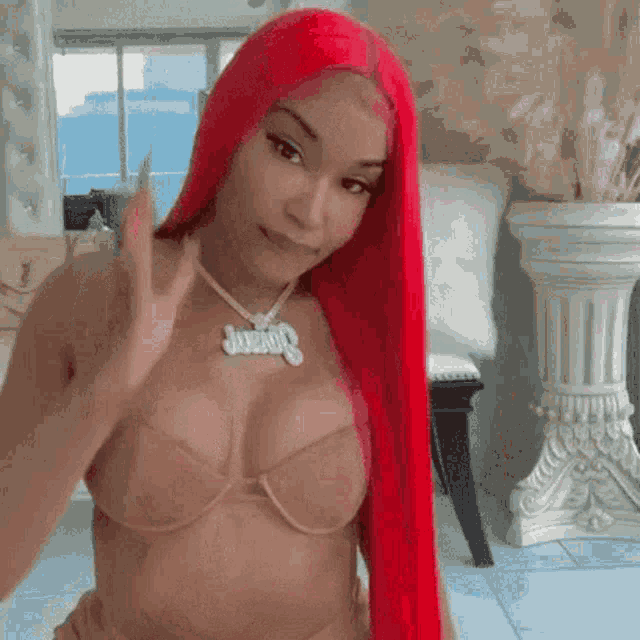 a woman with long red hair is wearing a bra and a necklace with a name tag on it .