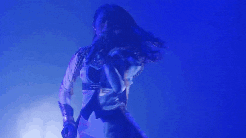 a woman is singing into a microphone on stage in front of a blue light .