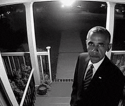 a man in a suit and tie is standing on a porch in front of a door .