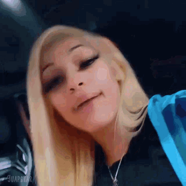 a close up of a woman 's face with blonde hair and a blue hoodie .
