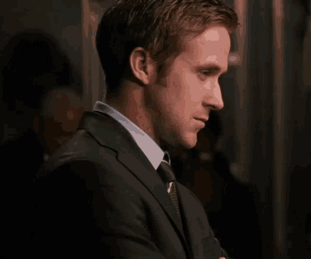 a man in a suit and tie looks to his left