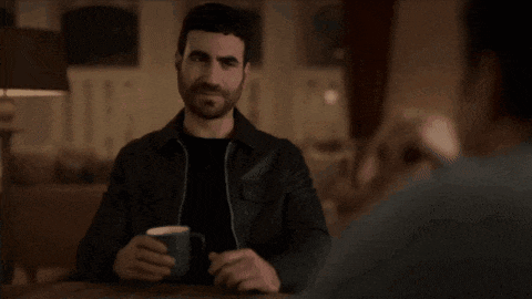 a man sitting at a table with a cup of coffee and the words " i love it " behind him