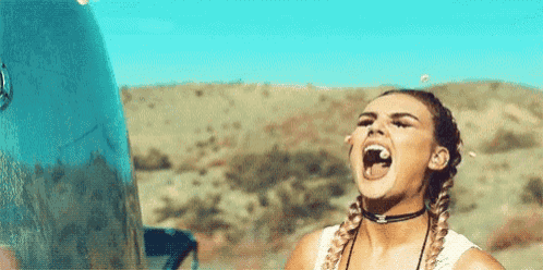 a woman is standing in front of a car with her mouth open and bubbles coming out of her mouth .