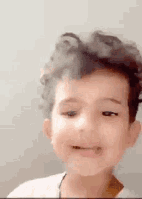 a young boy with curly hair is making a funny face .