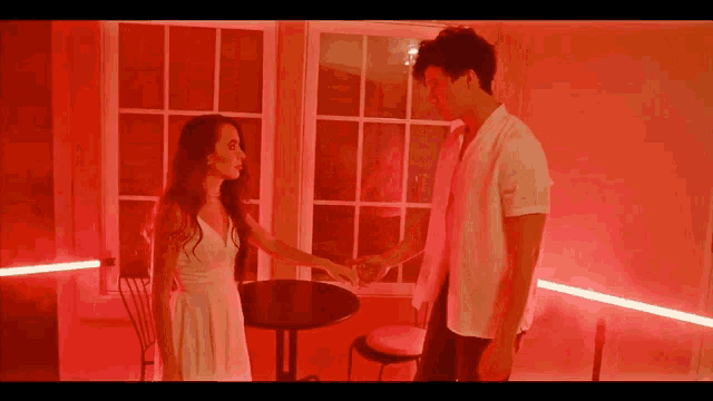 a man and a woman are standing next to each other in a room with red lights