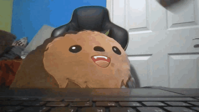 a stuffed animal with vampire teeth sits on a laptop keyboard