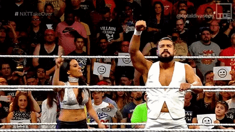 a man in a white vest is standing in a wrestling ring while a woman stands behind him