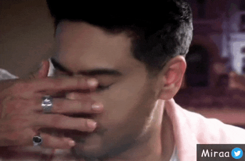a man with a ring on his finger covers his face with his hand