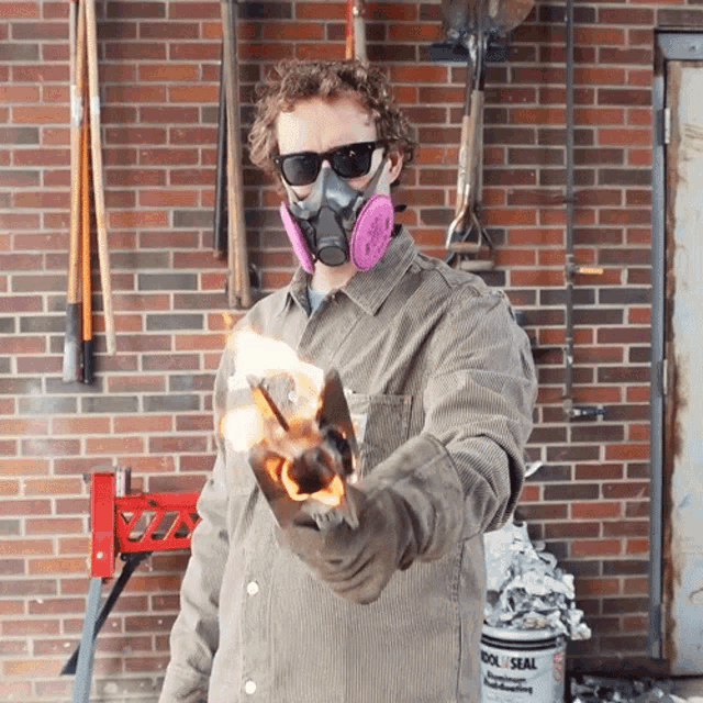 a man wearing a gas mask is holding a piece of metal in front of a brick wall