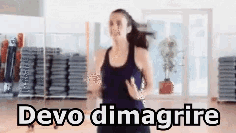 a woman is running in a gym and the words devo dimagrire are written on the screen .