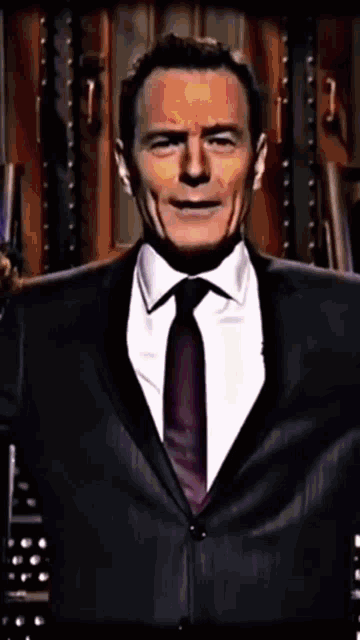 a man in a suit and tie is standing in front of a wall