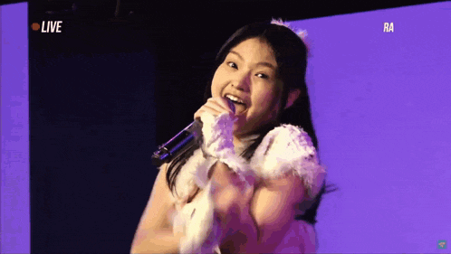 a girl singing into a microphone in front of a live screen