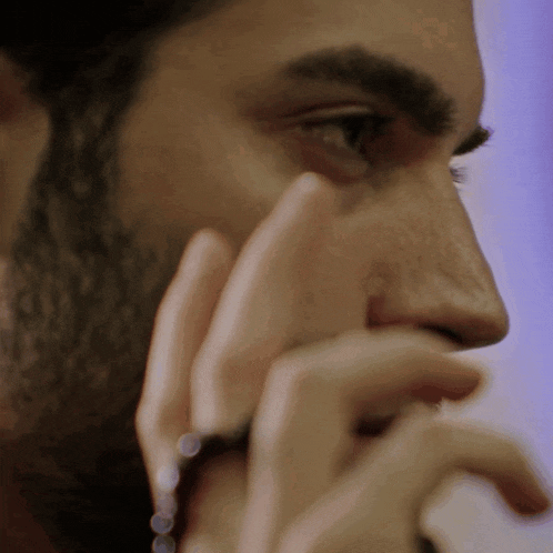 a man with a beard is covering his face with his hand