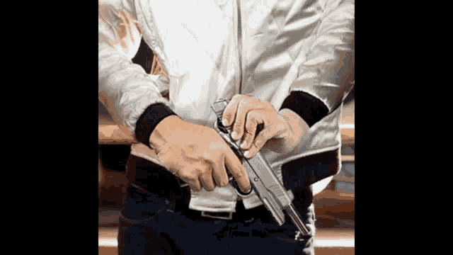 a man in a white jacket holds a gun in his hand
