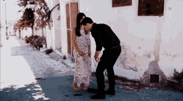 a man and a woman are standing next to each other in front of a white building