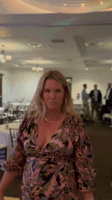 a woman in a floral dress is standing in a room with people behind her