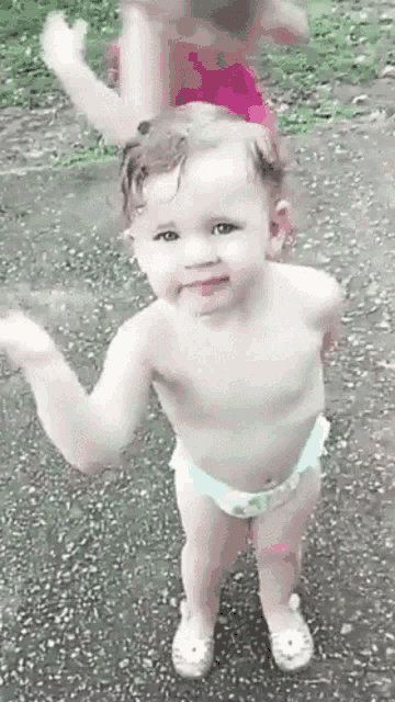 a baby girl in a diaper is standing on the ground .