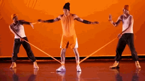 a man in an orange tank top and shorts is holding a rubber band