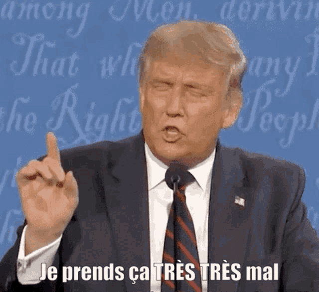 a man in a suit and tie is giving a speech and says je prends ca très tres mal