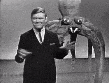 a man in a suit and tie is standing next to a giant octopus .