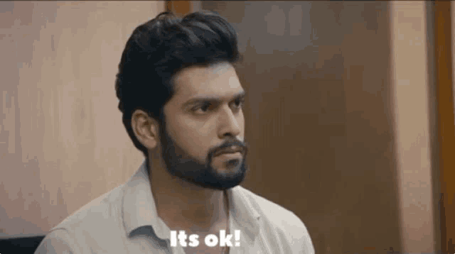 a man with a beard is sitting in a chair and saying `` it 's ok '' .