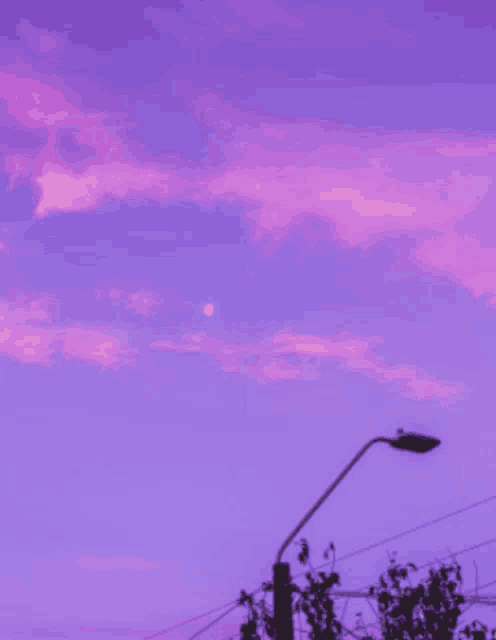 a street light in front of a purple sky with the moon