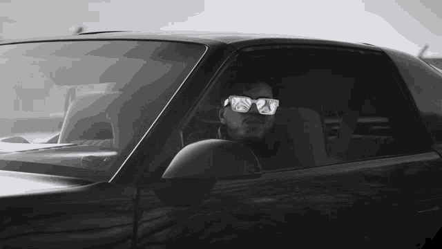 a man wearing sunglasses sits in a car