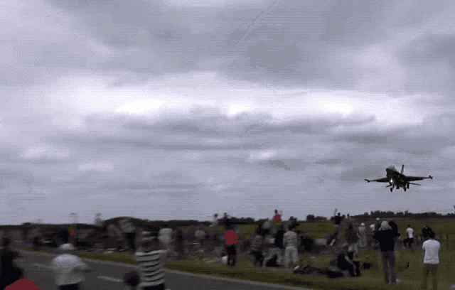 a fighter jet is flying over a crowd of people on a cloudy day