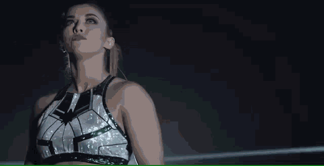 a woman is standing in a dark room wearing a crop top and earrings .