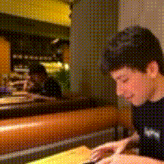 a man is sitting at a table in a restaurant looking at something