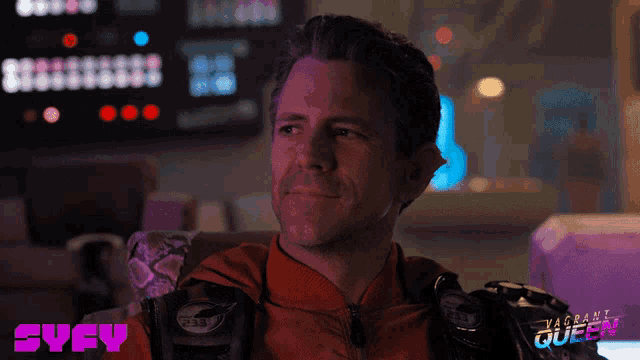 a man in a red jacket is smiling in front of a screen that says svcy