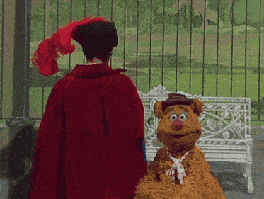 a man in a red cape stands next to a stuffed animal