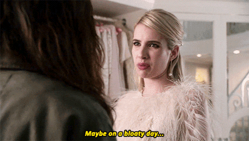 a woman in a white fur coat is talking to another woman and says " maybe on a bloaty day "