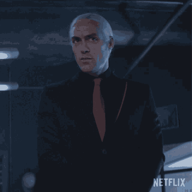 a man in a suit and tie stands in front of a netflix logo