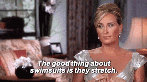 a woman is sitting on a couch in a living room talking about swimsuits and stretch .