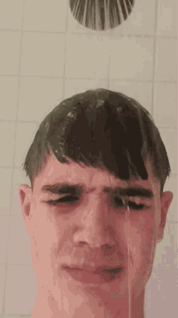 a young man is taking a shower and the water is coming out of his head