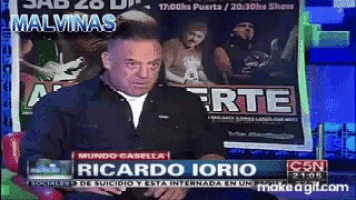 a man is sitting in front of a sign that says malvinas on it
