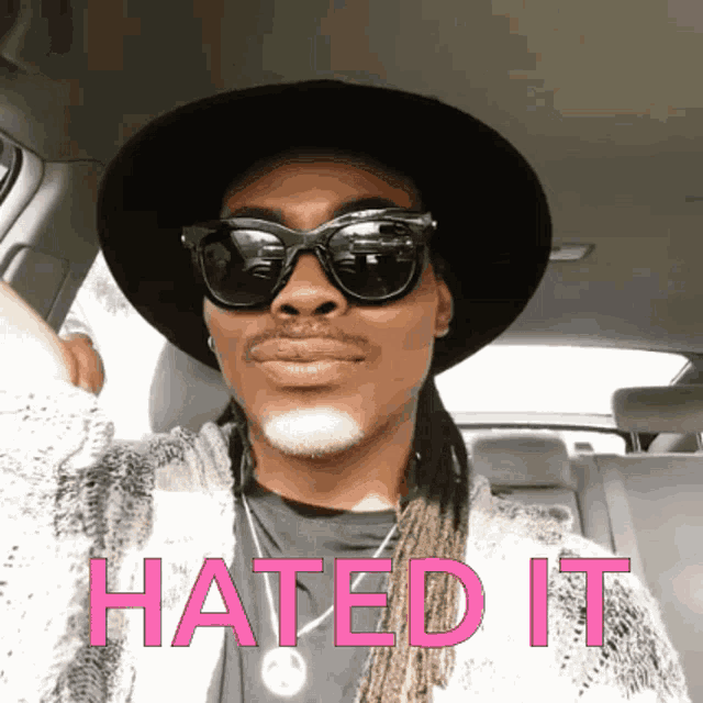 a man wearing a hat and sunglasses is sitting in a car with the words hated it written above him