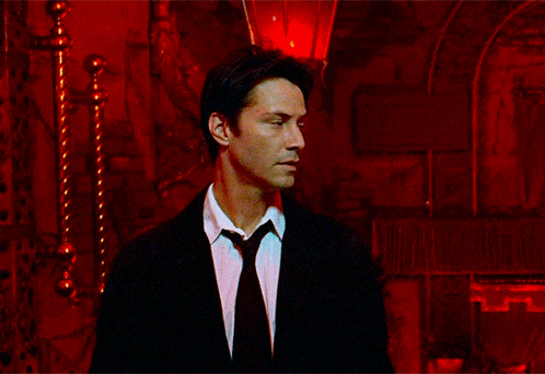 a man in a suit and tie stands in a red room