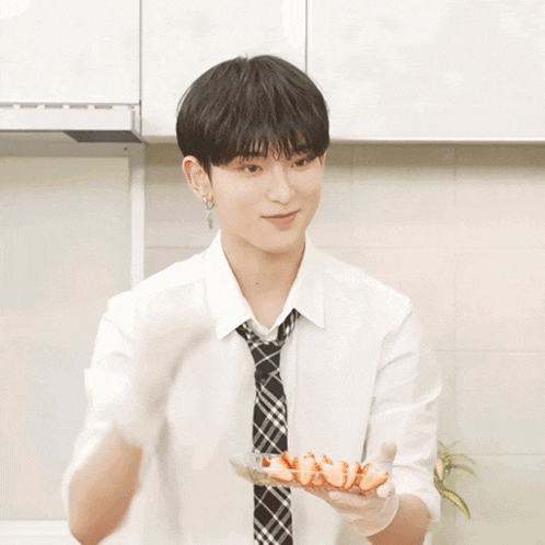 a man in a white shirt and tie is holding a plate of strawberries