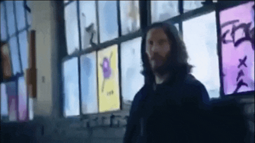 a man with a beard is standing in front of a window .