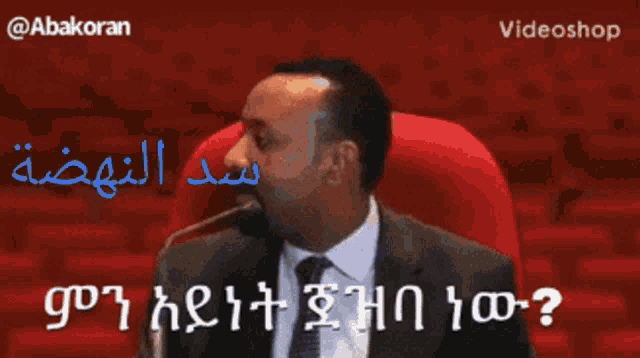 a man in a suit and tie is speaking into a microphone in a red chair