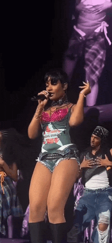 a woman singing into a microphone on a stage