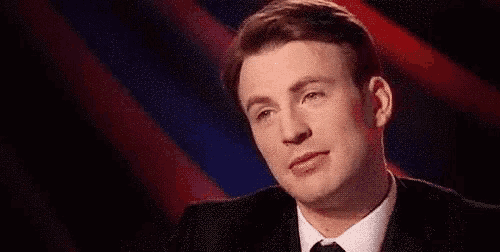 a man in a suit and tie is looking at the camera .